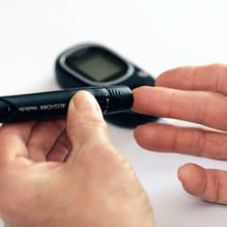 Person pricking their finger to check their blood sugar with a diabetes monitor