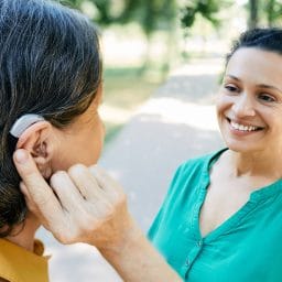Woman with hearing aid chatting with her friend outside.