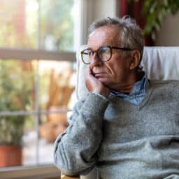 Senior man looking out of window at home
