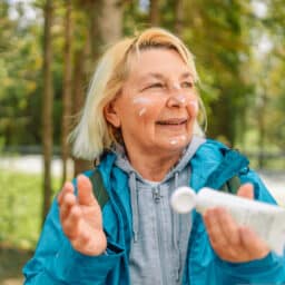 Woman applying sunscreen in the woods