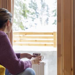 Woman with a hearing aid looking out a snowy window