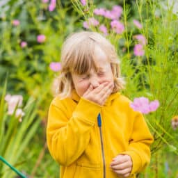 Young girl sneezes in flowers