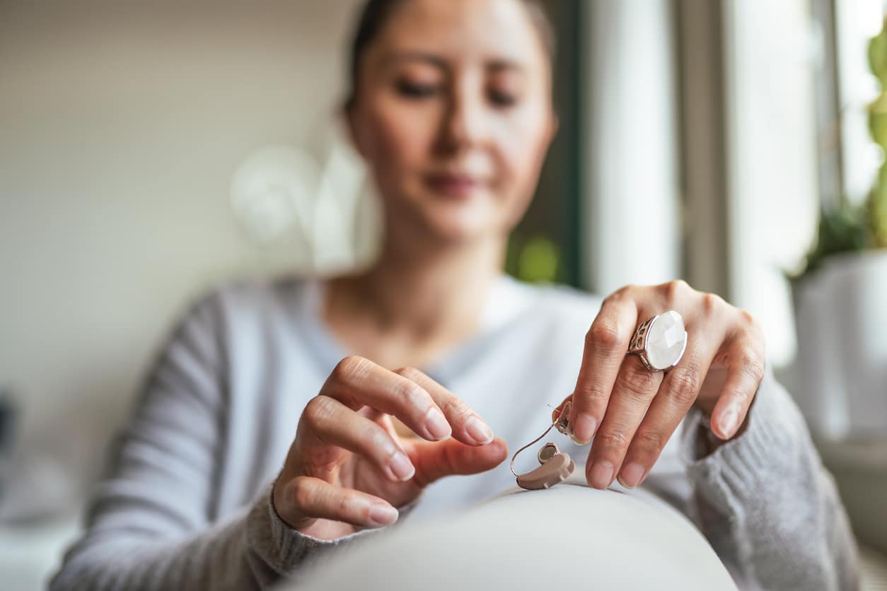 Woman inserting battery into the Hearing Aid.
