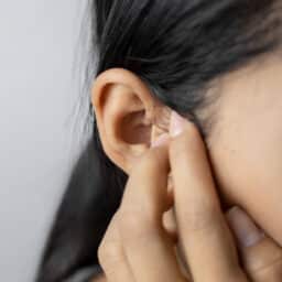 Woman with somatic tinnitus holding her ear.