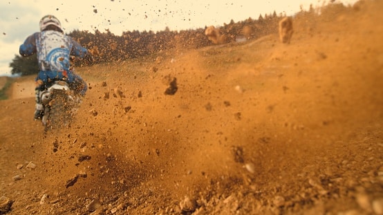 Dirt flies as a motocross rider races over the track.